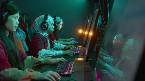 Focused Girl in Hijab and Headset Playing Online Shooter with Team in Club