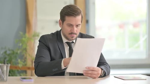 Man Celebrates Business Success Reading Document