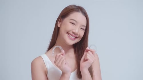 Woman Smiles Holding Clear Dental Aligners