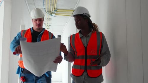 Construction Workers Review Blueprints on Construction Site