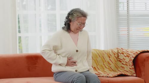 Senior Woman Experiencing Abdominal Pain on Sofa