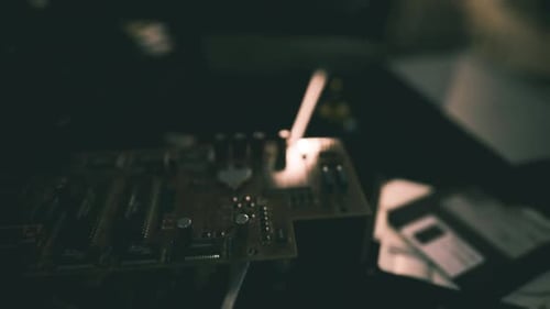 Exploring Electronic Circuit Boards with Tools in a Dimly Lit Workspace