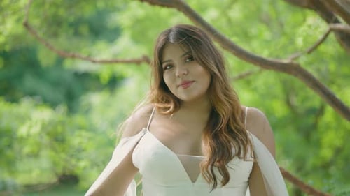 Woman Poses in White Dress in Green Setting