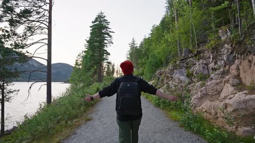 Back View of a Man Walking in the Forest a Black Backpack Hanging on His Back