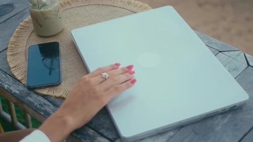 Woman Opens Laptop on Outdoor Wood Table