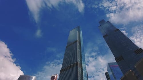 Looking Up at Tall Modern Glass Skyscrapers Against a Blue Cloudy Sky These Buildings House