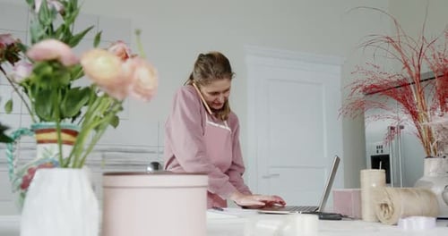 Young Girl Saleswoman in Flower Shop Florist Business Lady Talking on the Phone Smiling and Writing
