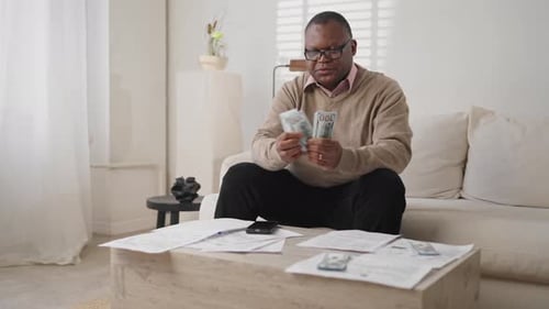 Man Counts Money at Home on the Couch