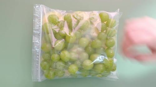Corte verduras y frutas en bolsas de celofán sobre un fondo verde, vista desde arriba de cerca.