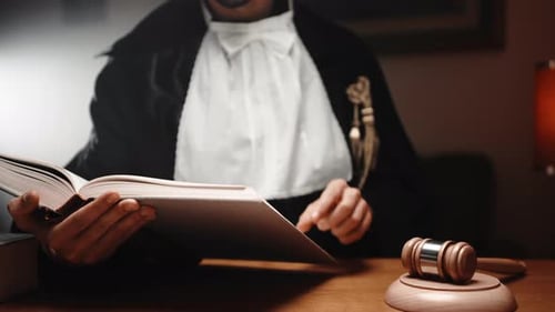 Man Reads Law Book with Gavel on Desk