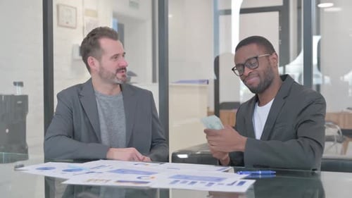 MIddle Aged Man Giving Money to African Man, Shaking Hand