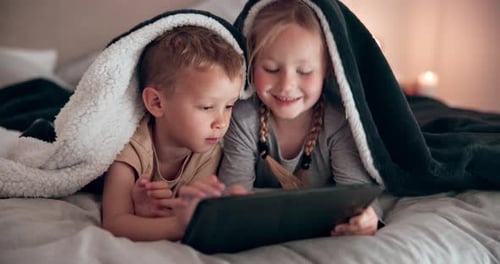 Children Watching Tablet Under Blanket on Bed