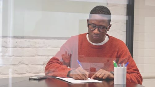 African Man Writing a Letter at Workspace