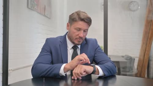 Mature Adult Businessman Using Smart Watch in Office