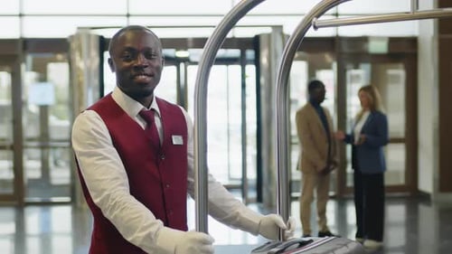 Cheerful Hotel Porter Posing with Luggage Cart