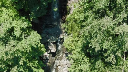 Aerial View Of A Hidden Waterfall Flowing Through Lush Forest