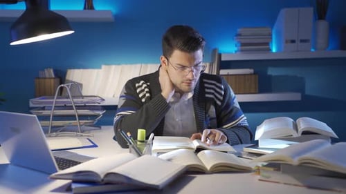 Man Studies with Laptop and Many Books at Night