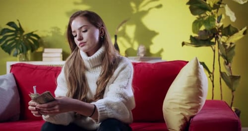 Woman Counting Money on Couch in Home