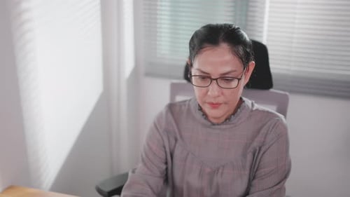 Asian woman typing on laptop keyboard sitting at office in online workspace with modern technology