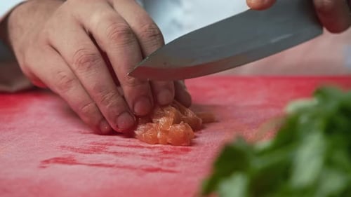 Closeup Shot of a Male Chef Cutting Orange Fish Flesh on a Chopping Board in a Home Kitchen Setting