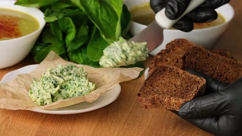 Hands Spreading Spinach Butter on Brown Bread