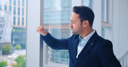 Gestresster Geschäftsmann fühlt sich frustriert und wütend am Fenster und denkt über ein schwieriges Problem nach