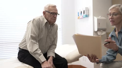 Senior doctor and patient review medical chart in exam room