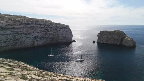 drone aerial view of sailboat anchored in protected bay at Dwejra, Gozo, Malta, cinematic 60FPS