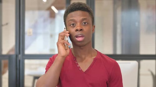 Young Man Talking on Smartphone Indoors