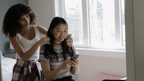 Friends Together: Woman Styles Friend's Hair in Bedroom