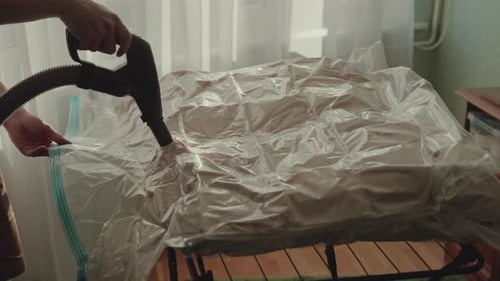 Person Vacuuming Air Out Of Plastic Storage Bag