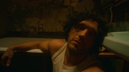 Man Resting Head Against Tub in Dark Bathroom