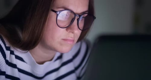 Focused Woman Looking at Computer Screen at Night