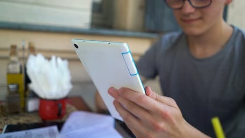 Young teenager browsing social media on tablet computer in urban cafe