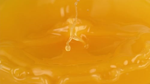 Vibrant orange slice falling into orange juice
