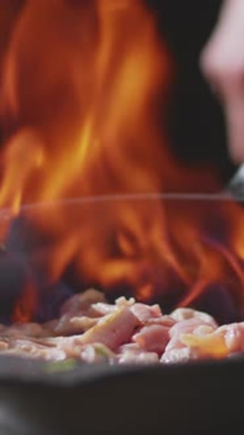 Close-up of Unrecognizable Chef Adding Flame to Chicken Pieces in skillet