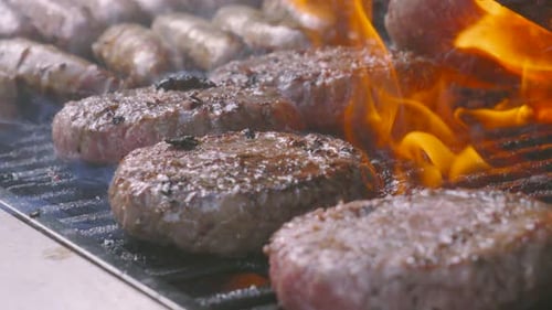 Flames On BBQ: Kochen Sie mit Pfeffer gewürzte Rinderburger über heißem Holzkohlefeuer
