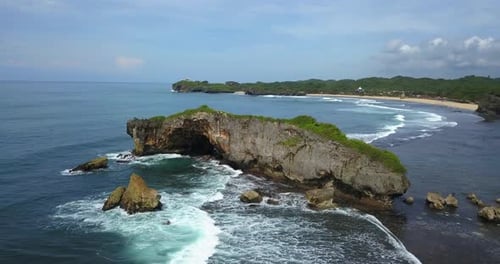 Drone view of shoreline with clusters of coral rocks that crushing by the wave on the tropical beach