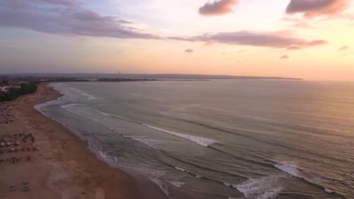 Aerial drone shot of surfers surfing at Canggu beach during the sunset, Bali, Indonesia.