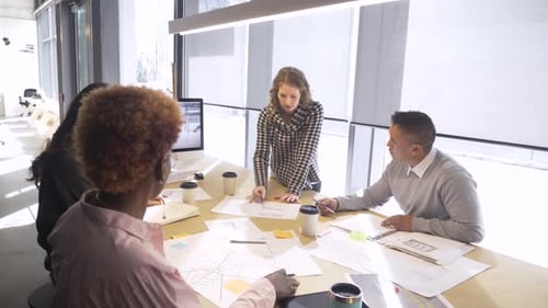 Coworkers Collaborate on Blueprints at Modern Office Workplace