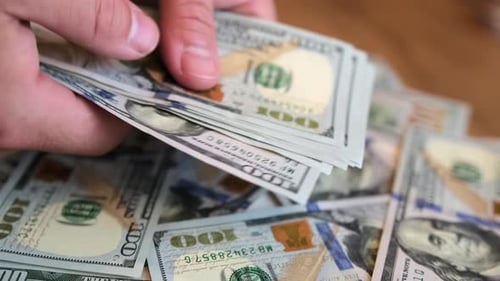 Male hands count 100 dollar bills on the background of money table and hand throw pack