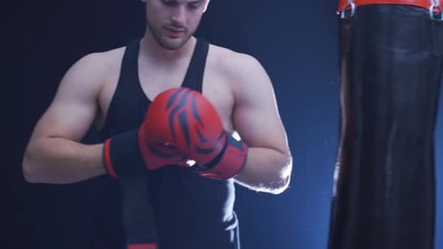 Man Puts on Boxing Gloves and Punches Bag