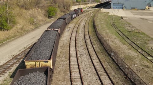 Heavy industrial railroad carts filled with coal hauled by train, aerial view
