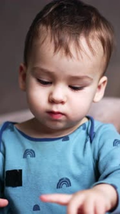 Un niño encantador y lindo se sienta en el suelo cerca del sofá jugando con juguetes.