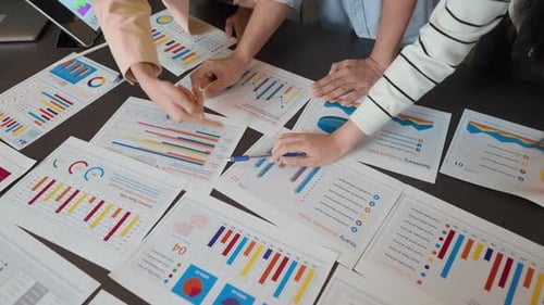 Close-up of hands pointing at colorful charts