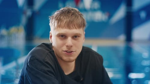 Junger Mann spricht während eines Interviews im Schwimmbad Porträt des Mannes, der in einem öffentlichen Schwimmbad spricht