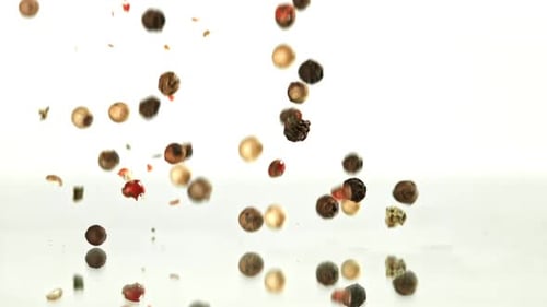Falling colorful peppercorns and herbs on white background