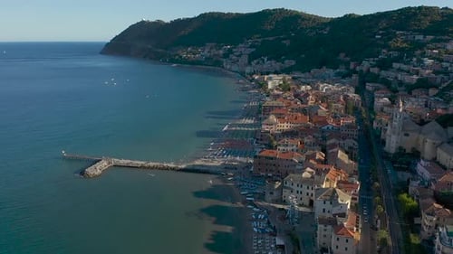 drone flying backwards from the city of Laigueglia, Liguria during sunset