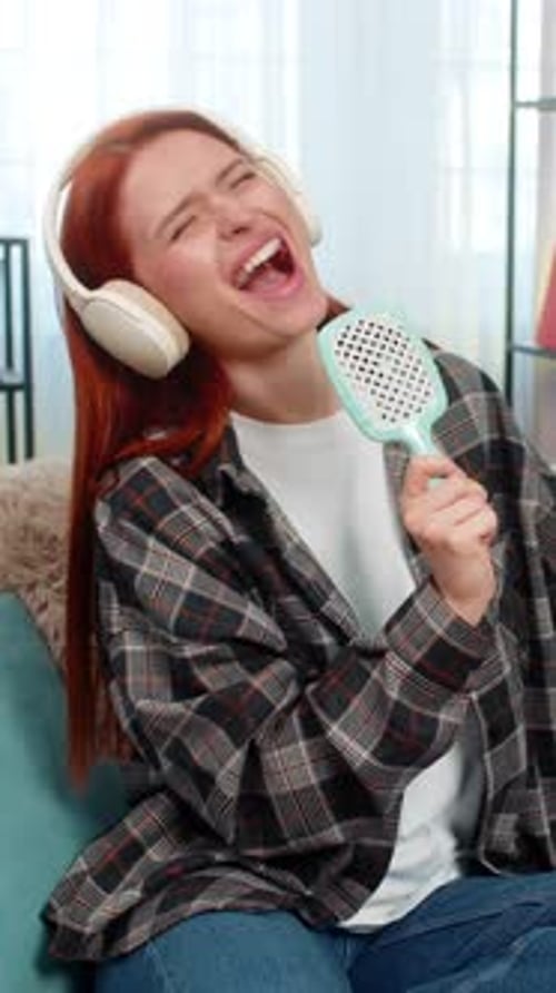 Excited woman singing into hairbrush at home