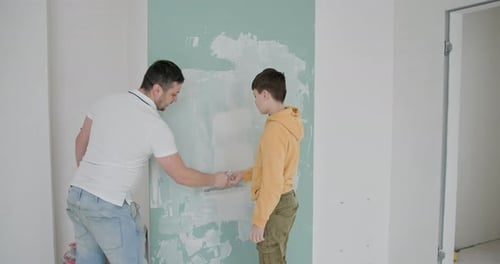 Man and Boy Plastering a Wall Together